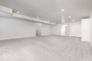 Below grade area with light carpet, a textured ceiling, and recessed lighting