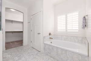 Full bath with a walk in closet and a garden tub