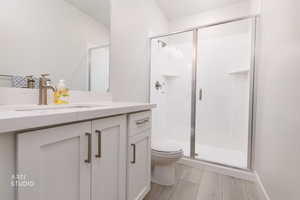 Full bath featuring vanity, a shower stall, and light wood finished floors