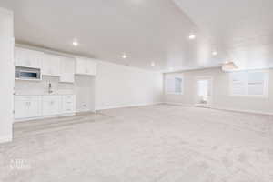 Unfurnished living room with light colored carpet and recessed lighting