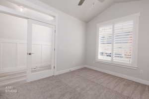 Unfurnished bedroom with vaulted ceiling, a ceiling fan, and carpet floors