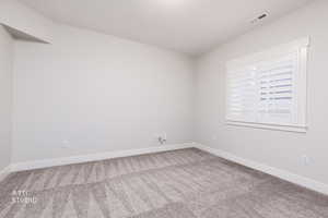 Empty room featuring baseboards and light colored carpet