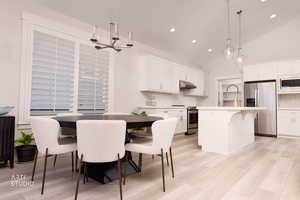 Dining room featuring lofted ceiling, light wood-type flooring, recessed lighting, and a chandelier