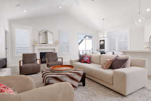 Living room featuring a high end fireplace, recessed lighting, wood finished floors, a ceiling fan, and a chandelier