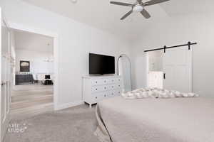 Bedroom featuring a barn door, light carpet, lofted ceiling, a ceiling fan, and a chandelier