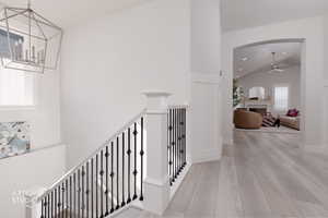Hallway with light wood-style flooring, recessed lighting, high vaulted ceiling, and a chandelier