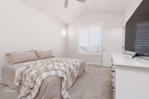 Bedroom with light colored carpet, vaulted ceiling, and ceiling fan
