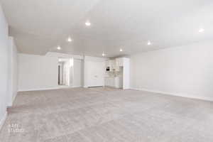 Unfurnished living room with light colored carpet, a textured ceiling, and recessed lighting