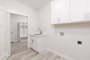 Washroom featuring hookup for a washing machine, cabinet space, light wood-style flooring, and hookup for an electric dryer