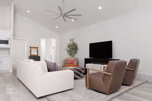 Living area featuring light wood-type flooring, high vaulted ceiling, ceiling fan, recessed lighting, and arched walkways