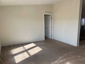 Unfurnished bedroom featuring stainless steel fridge with ice dispenser, carpet, and ensuite bathroom