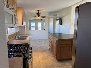 Kitchen featuring stainless steel appliances, brown cabinetry, healthy amount of natural light, and a ceiling fan