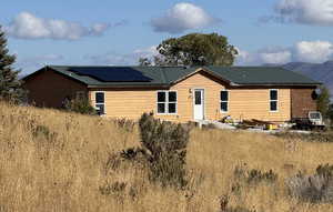 Back of property with roof mounted solar panels, a metal roof, and a mountain view