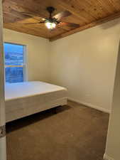 Bedroom featuring wooden ceiling, dark colored carpet, and ceiling fan
