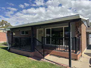 Rear view of property with a wooden deck, brick siding, and a yard