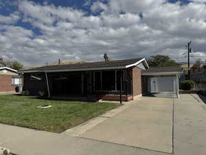 Ranch-style home featuring brick siding, a wooden deck, a front yard, and roof with shingles