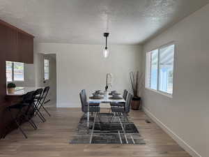 Dining area with light wood-style floors and a textured ceiling