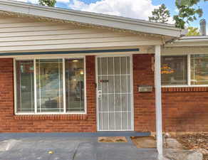 View of exterior entry featuring brick siding and covered porch