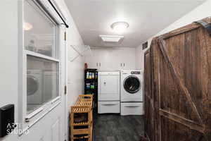 Laundry area with a barn door, dark wood-style floors, and separate washer and dryer