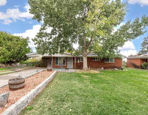 Ranch-style house featuring a front yard, brick siding, and concrete driveway