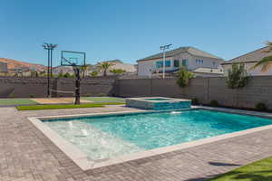 View of swimming pool featuring a fenced backyard, a residential view, a pool with connected hot tub, and a patio