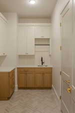 Bar area with brown cabinetry, light countertops, and white cabinetry