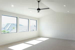 Carpeted spare room featuring wood walls, lofted ceiling, recessed lighting, and a ceiling fan