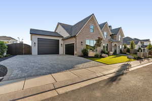 View of front facade with decorative driveway, a garage, and brick siding