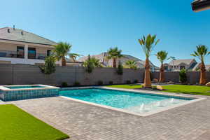 View of swimming pool featuring a patio area, a fenced backyard, and a pool with connected hot tub