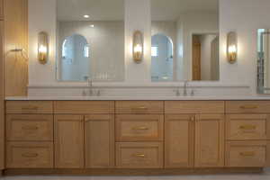 Full bathroom with double vanity, walk in shower, and light tile patterned flooring