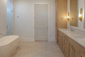 Full bath with a soaking tub, light tile patterned floors, double vanity, and a shower stall