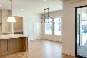 Unfurnished dining area featuring a decorative wall, recessed lighting, light wood-type flooring, a chandelier, and wainscoting