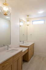 Bathroom featuring a chandelier, two vanities, and light tile patterned floors