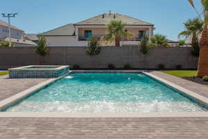 View of swimming pool featuring a pool with connected hot tub, a fenced backyard, and a patio area