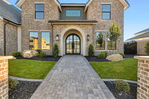 Doorway to property with brick siding and a yard