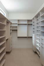 Walk in closet with light colored carpet