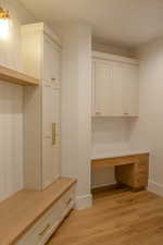 Mudroom with built in desk and light wood finished floors
