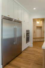 Kitchen featuring appliances with stainless steel finishes, light wood-type flooring, recessed lighting, and white cabinetry