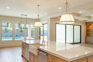 Kitchen with an island with sink, light wood finished floors, recessed lighting, pendant lighting, and stainless steel dishwasher