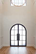 Entryway with light wood-style floors, a high ceiling, and arched walkways