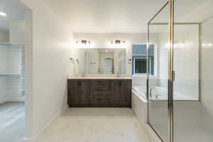 Full bathroom with double vanity, a garden tub, a shower stall, and light marble finish floors