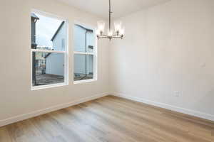 Unfurnished dining area with a chandelier and light wood-style flooring