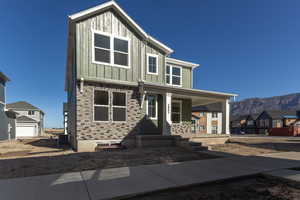 View of front of home with board and batten siding, covered porch, a mountain view, and a residential view