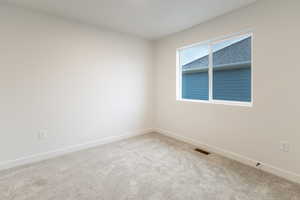 Unfurnished room featuring light carpet and baseboards