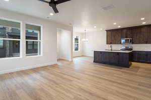 Kitchen featuring recessed lighting, a chandelier, hanging light fixtures, backsplash, and a center island with sink