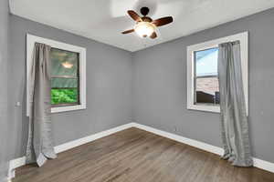 Unfurnished bedroom with hardwood / wood-style flooring, a ceiling fan, and a textured ceiling
