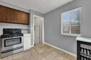 Kitchen featuring stainless steel electric range, light countertops, and light tile patterned floors