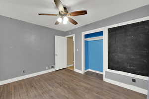 Unfurnished bedroom with dark wood-style flooring, ceiling fan, and a closet