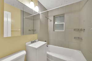 Bathroom featuring shower / washtub combination, vanity, and a textured ceiling