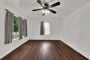 Empty room with dark wood-type flooring and a ceiling fan